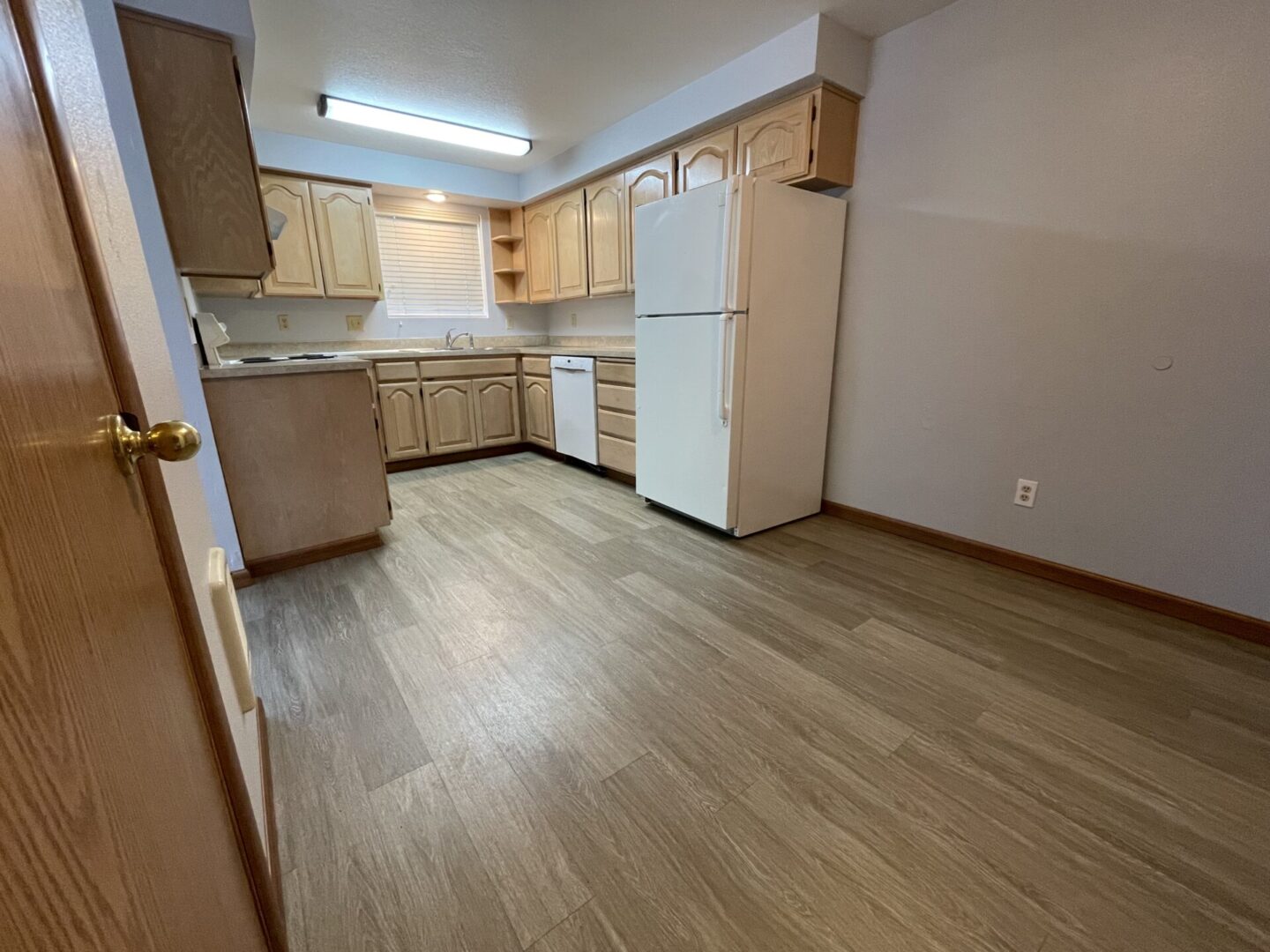 Empty kitchen with wooden cabinets and light flooring.