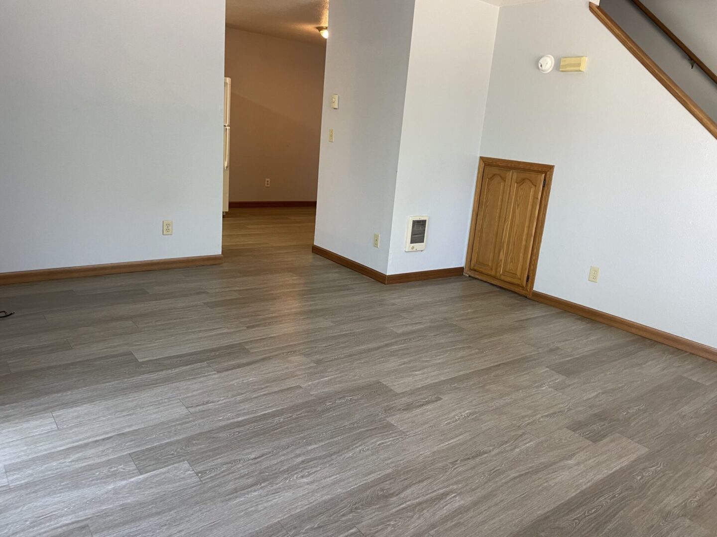 Empty room with light wooden flooring and white walls.