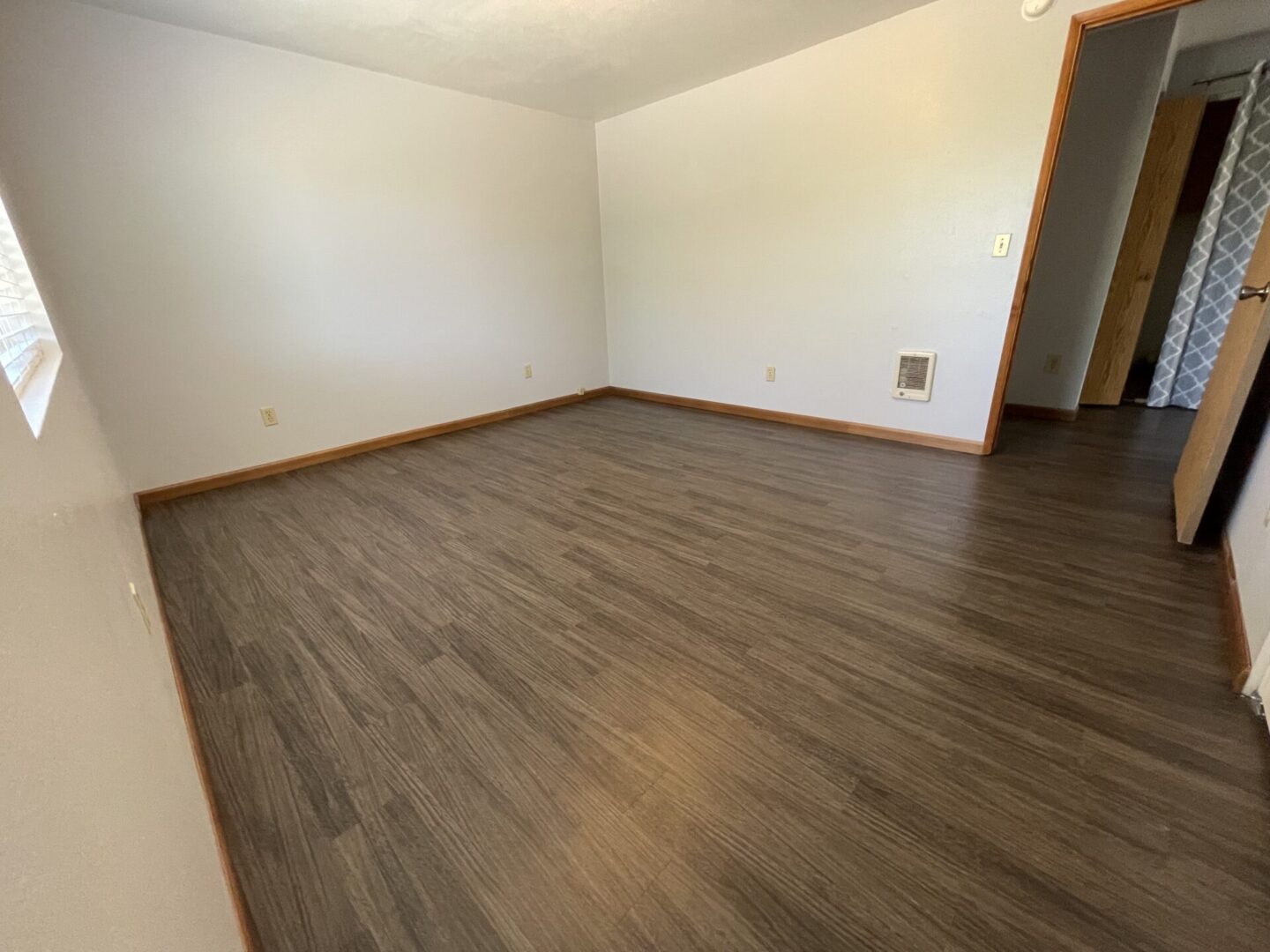 Empty room with wood-look flooring and white walls.